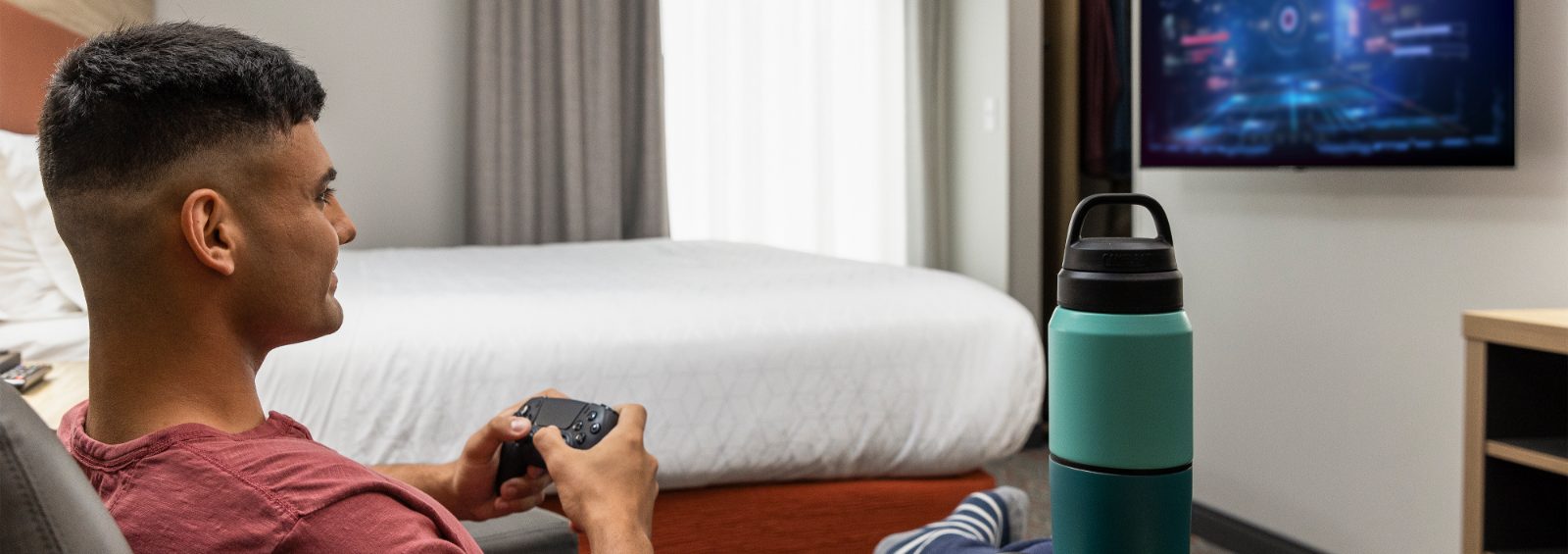 Man gaming on the large screen TV in bedroom suite